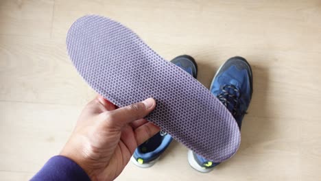 hand holding shoe insole and blue hiking shoe