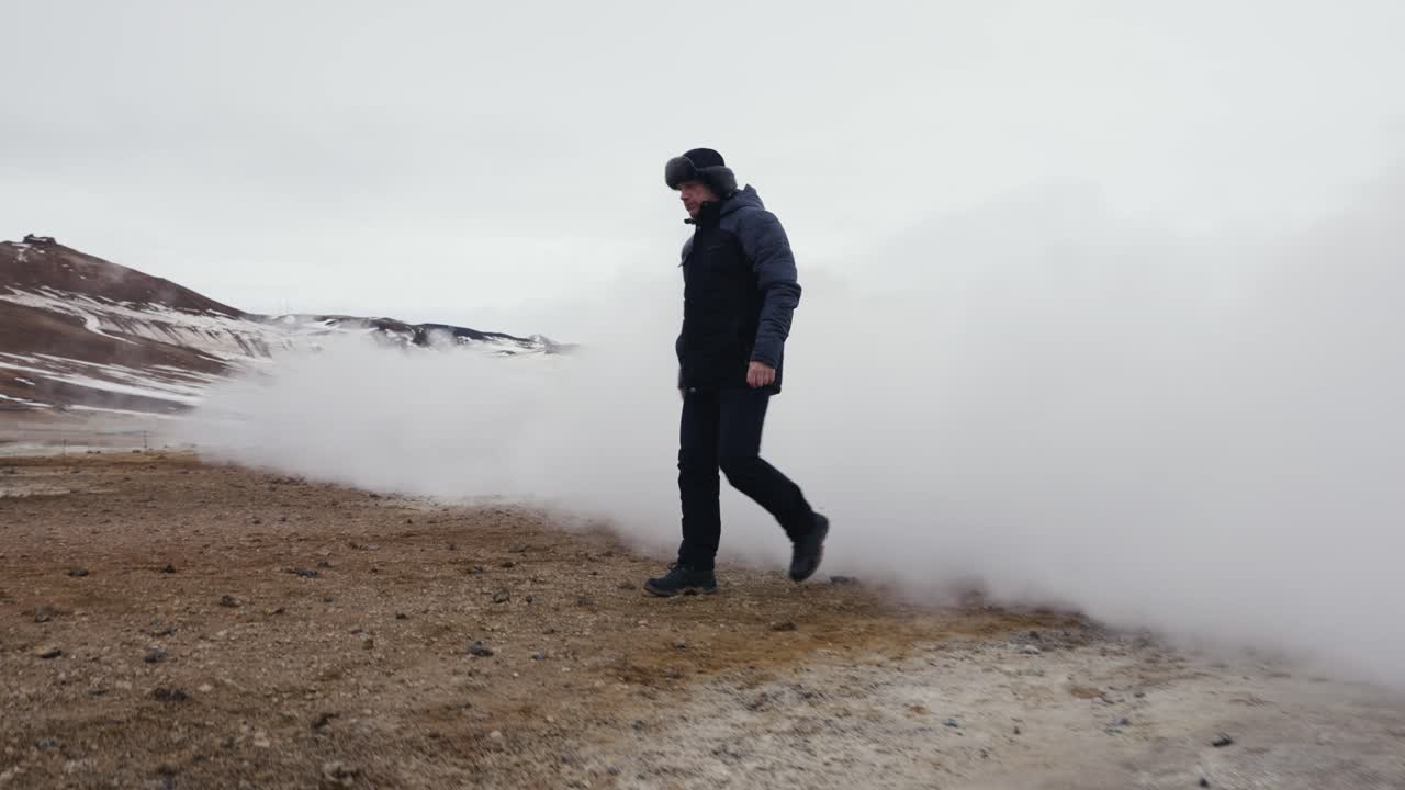 турист проходит сквозь густое облако пара из вулканического исландского дыхательного отверстия