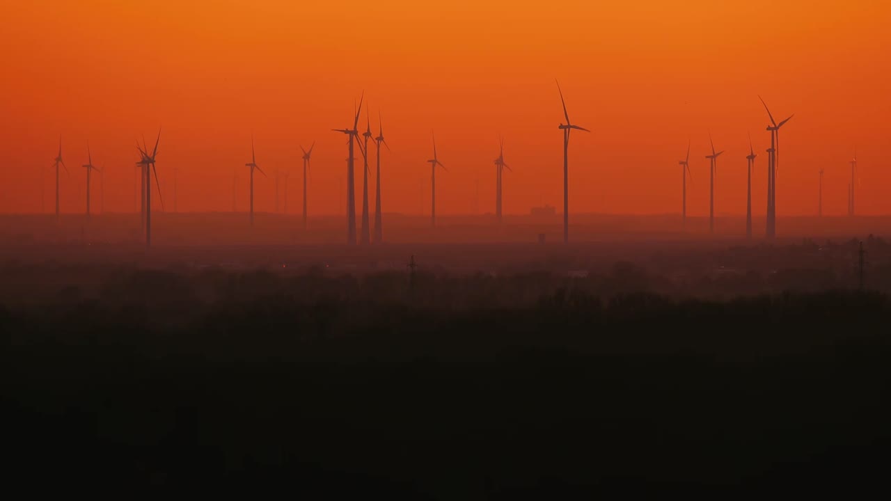 Medium shot of several windd turbines working in summer evening.