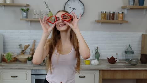 joyful young girl vegan dancing holding fresh red slice of bell pepper on eyes. healthy nutrition