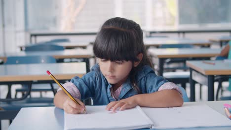 Focused-primary-school-pupil-girl-holding-pencil-and-drawing