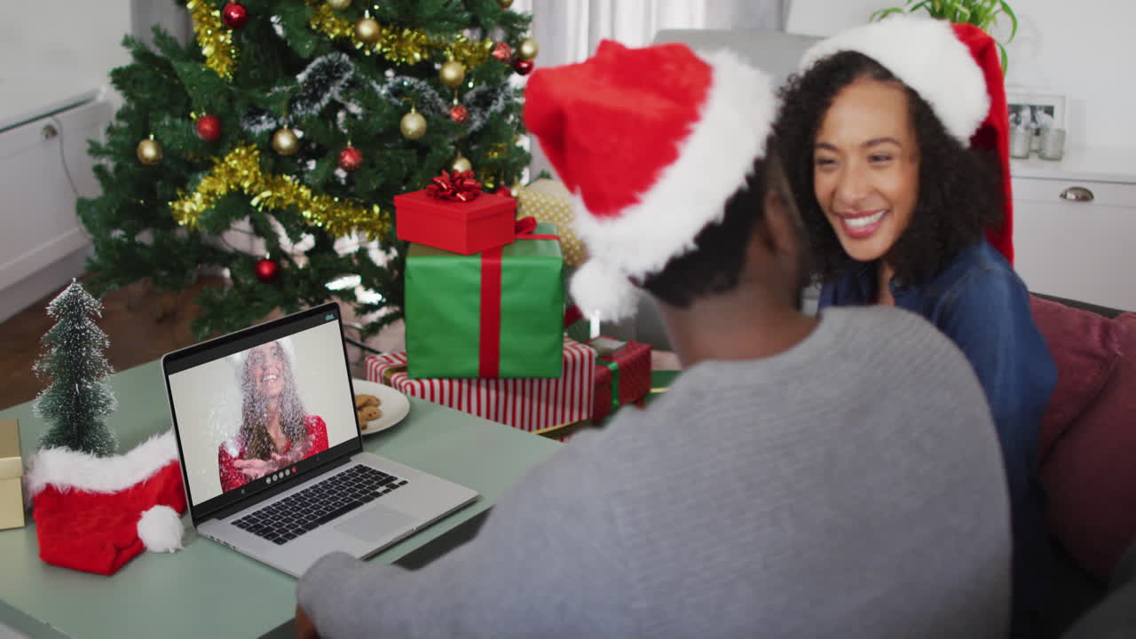 feliz pareja afroamericana en videollamada en computadora portátil con amiga en tiempo de navidad