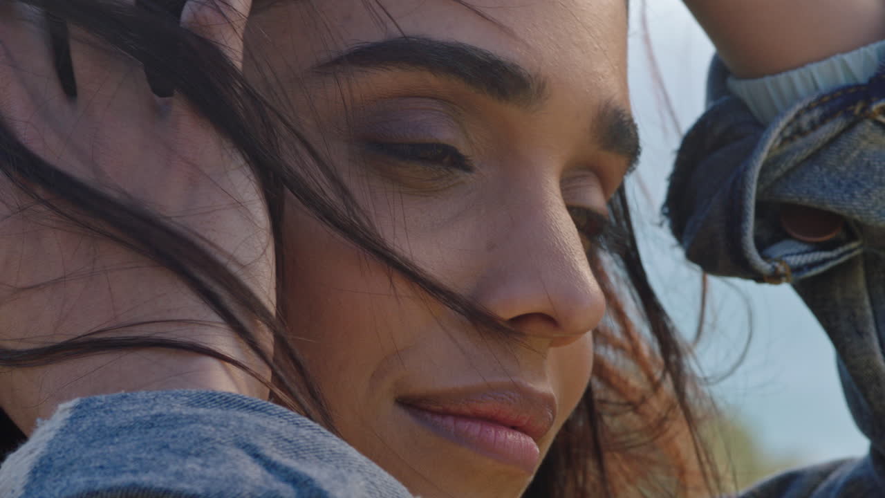 retrato en primer plano de una hermosa mujer india disfrutando de un tranquilo día soleado relajándose en las vacaciones de verano corriendo las manos a través del cabello