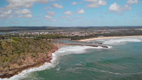 aerial drone view over waves hitting the shore of the evans head town, sunny day