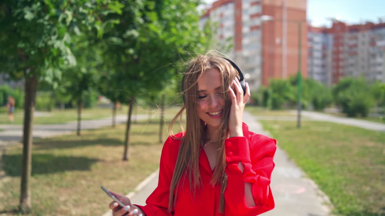 Girl listening to music in headphone. Attractive young woman listening to music in headphone, use smartphone at city walk