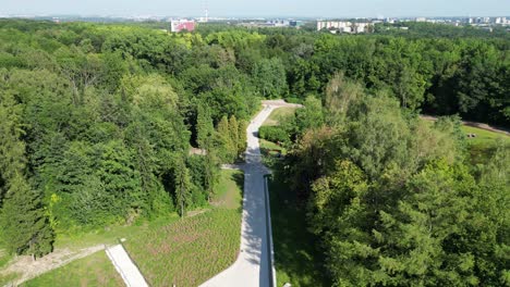 Aerial-wiev-of-park-during-a-summer-day-surrounded-by-lush-greenery,-grass-and-trees-under-a-blue-sky