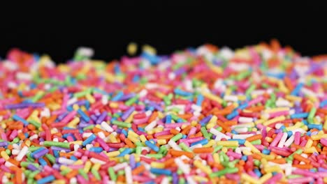 a close-up view of multicolored sprinkles creating a vibrant, textured surface against a dark background.