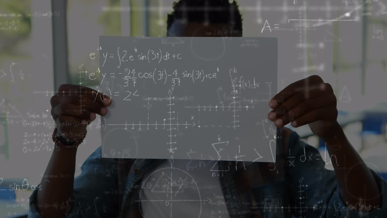 Mathematical equations floating against african american boy holding a paper at elementary school