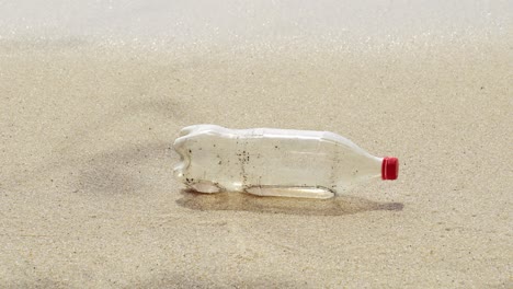 recipiente de plástico de bebida arrojado a la playa de arena