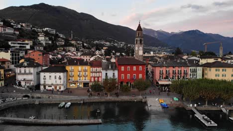 sobrevuelo aéreo a lo largo del paseo junto al lago de ascona, ticino a orillas del lago maggiore en la suiza italiana al final de un día de verano con casas coloridas y la torre de la iglesia a la vista