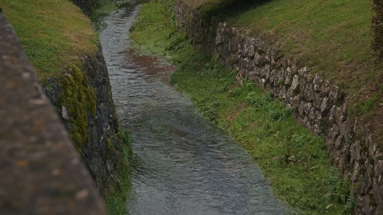 Clear stream flowing between mossy stone walls in Kumrovec, Croatia