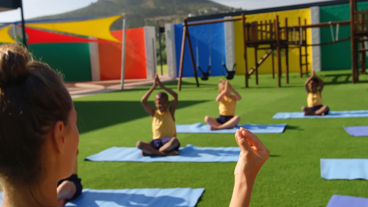 vista trasera de una maestra enseñando a los escolares a realizar yoga en el patio de recreo de la escuela 4k