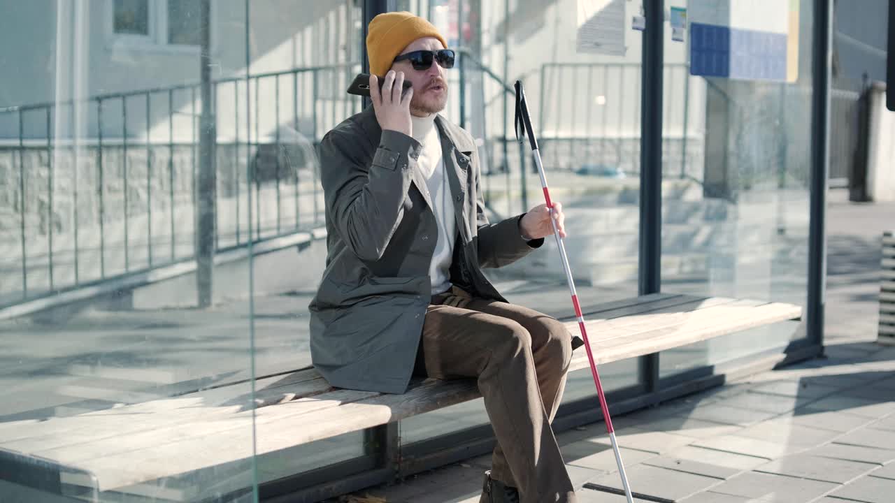 Blinded man waiting for bus at a bus station