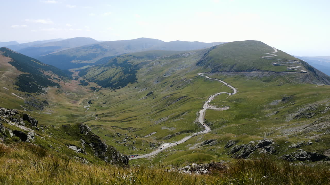 Ampia panoramica verso destra che rivela il paesaggio montano della Transalpina e le strade tortuose a mezzogiorno