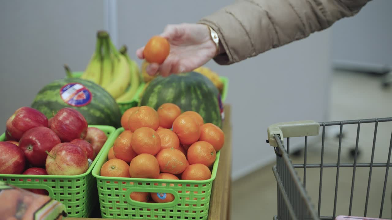 Shopper putting fruit into grocery cart. Fresh produce fruits.