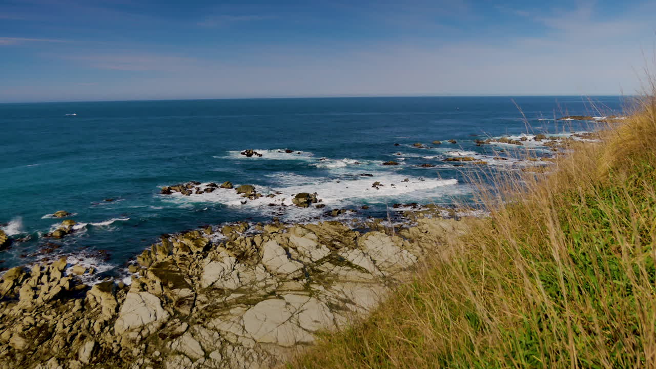 Smuk kystlinje fra Kaikoura på en solskinsdag med klippekyst og brusende bølger fra havet.