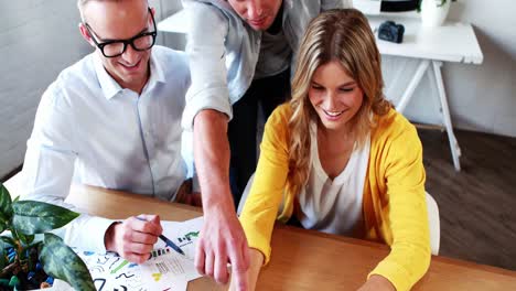 Businesswoman-interacting-with-coworkers-while-working-on-laptop