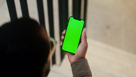 person holding smartphone with green screen display