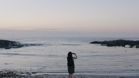 Porträt-Einer-Brünetten-Frau-Am-Strand,-Die-Mit-Dem-Telefon-Ein-Foto-Vom-Meer-Macht