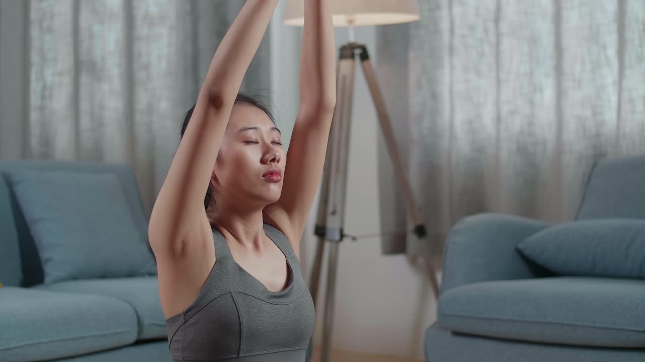retrato de cerca de una joven atleta asiática haciendo yoga en la postura de sukhasana durante el entrenamiento en la alfombra de yoga en casa. estilo de vida saludable, fitness, bienestar y atención plena