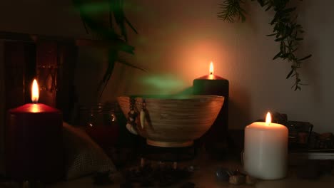 detail of a potion making witch room, with green steam coming out from a wooden bowl, animal teeth hanging from it, candles with flickering flames, old books, glasses and herbs in the background