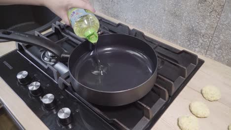 a woman's hand lights the gas under the pan and pours oil on it