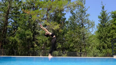 una mujer hace yoga junto a la piscina