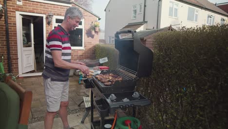 adult caucasian man having fun cooking meat on barbecue grill in home garden