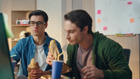 speaking colleagues having meal looking computer closeup. businessmen eating