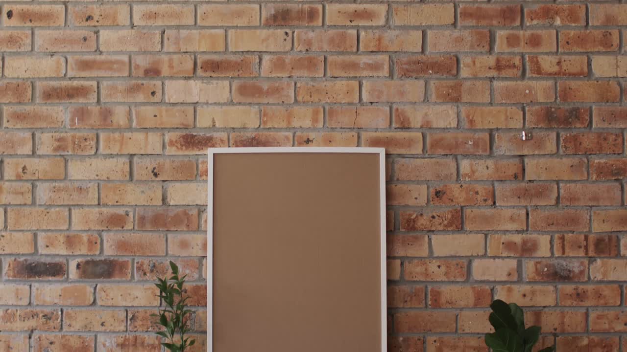 marco de madera y planta en el escritorio con espacio de copia contra la pared de ladrillo