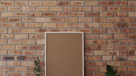 Wooden-frame-and-plant-on-desk-with-copy-space-against-brick-wall