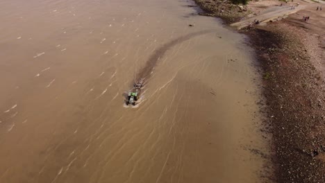 Vista-Aérea-Del-Tractor-Que-Ingresa-Al-Agua-Para-Sacar-El-Bote-Del-Río-De-La-Plata-En-Buenos-Aires,-Argentina