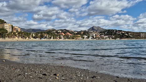 La-Malagueta-Beach-on-a-Sunny-Day-with-waves-Slowly-Breaking-on-the-Shoreline-and-Fast-Moving-Clouds