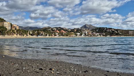 la playa de la malagueta en un día soleado con olas que se rompen lentamente en la costa y nubes que se mueven rápidamente