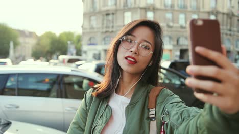 셀카 사진을 찍는 동안 스마트폰 카메라에 포즈를 취한 안경을 쓴 행복한 아름다운 젊은 여성의 클로즈업