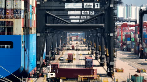 truck carrying a container turns into a lane under the container cranes in the port of hong kong while loading the giant vessel