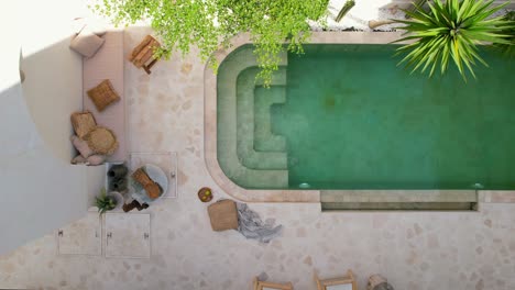 aerial top down of bohemian furniture next to tropical pool in a white bali villa