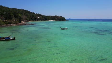 vista aérea de una playa de una isla tropical con agua turquesa que muestra barcos de cola larga esperando a los turistas en tailandia