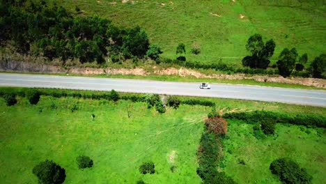 Safari-Vehicle-Driving-On-Scenic-Road-In-Kenya,-East-Africa---aerial-drone-shot