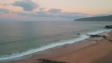 calm waves crashing shoreline drone view. cloudy sunset illuminating coastline
