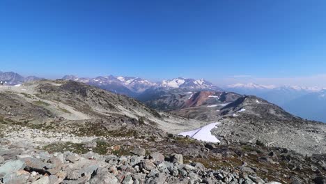 POV-pointing-down-to-the-feet,-the-n-lifting-up-the-camera-showing-a-wide-landscape-chain-of-mountains