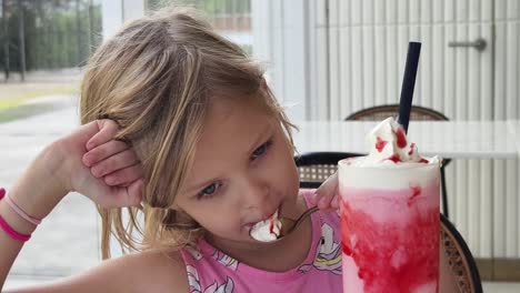 una niña disfrutando de un batido de fresa