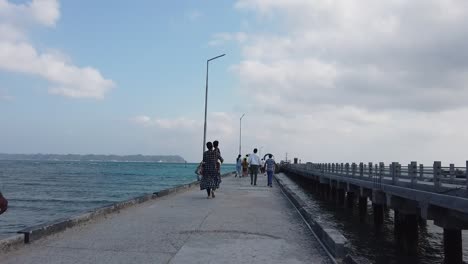 A-woman-in-traditional-indian-clothing-carries-her-child-along-a-jetty-leading-to-an-inter-island-ferry-in-the-andaman-islands-in-india