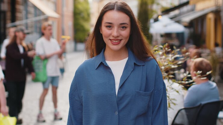 Una giovane donna felice sorridendo guardando via sognando riposando buone notizie sentendosi soddisfatta per la strada della città
