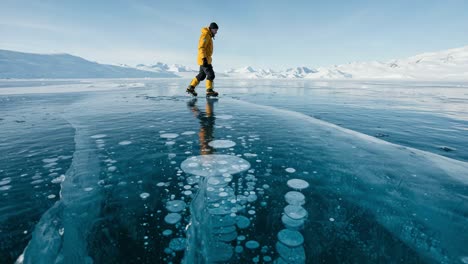 a solitary figure in a vibrant yellow jacket traverses the crystalline blue ice surface, surrounded by captivating patterns and bubbles in a serene winter landscape