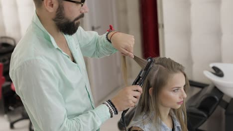 hairstylist straightening a woman's hair in a salon