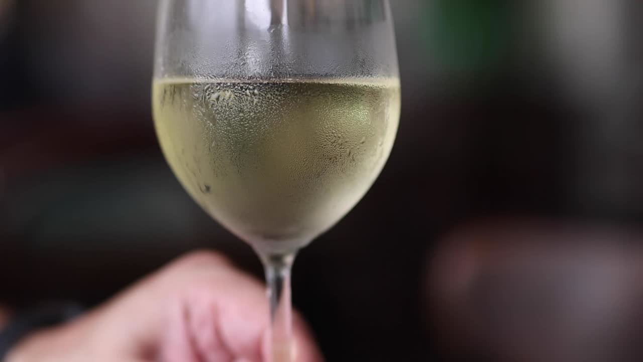 Primo piano della condensa su un bicchiere di vino mentre del vino bianco ruota delicatamente al suo interno