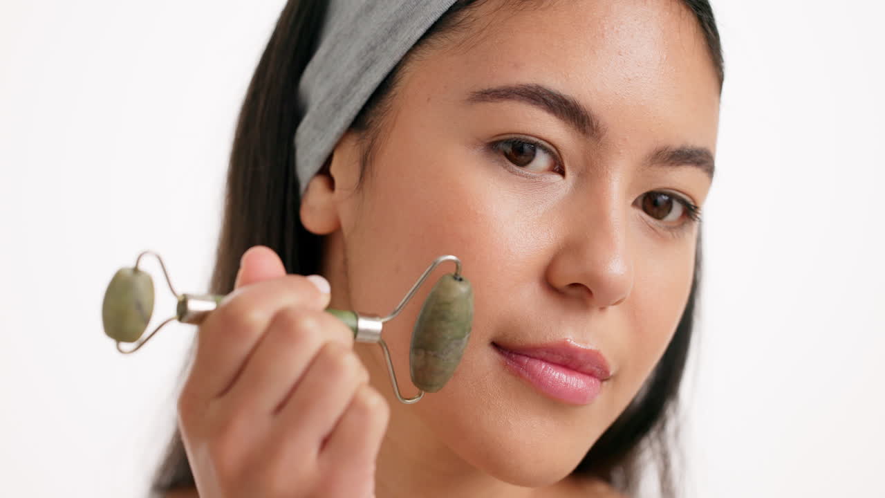 mujer usando un rodillo de jade para el masaje facial