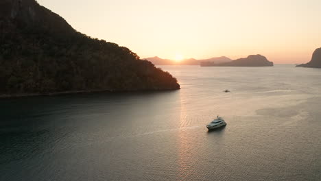 Antena-Que-Muestra-Un-Gran-Yate-Con-Puesta-De-Sol-En-El-Puerto-De-El-Nido,-Palawan,-Filipinas