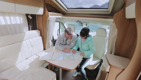 couples in rv camper looking at the local map for the trip.